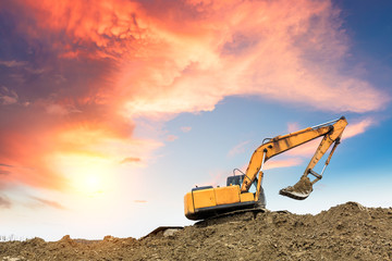 Excavator working at construction site on sunset