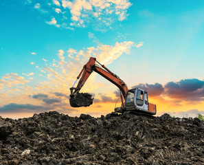 Excavator working at construction site on sunset