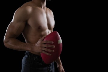 Muscular American football player holding a football in his hand