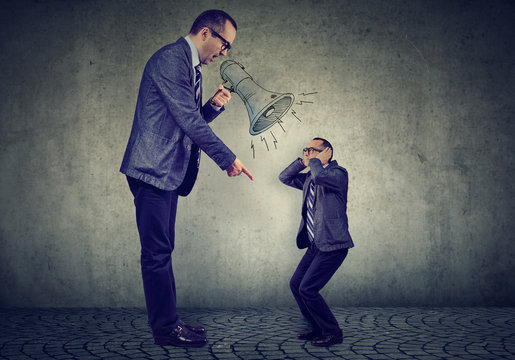 Angry mature business man boss screaming at small himself in megaphone