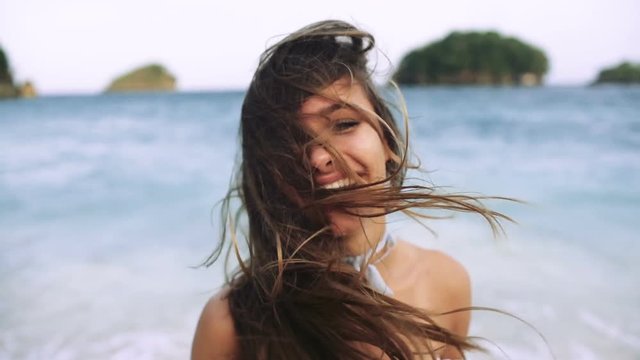 Sexy girl with beautiful smile and long hair laughing on the beach and running