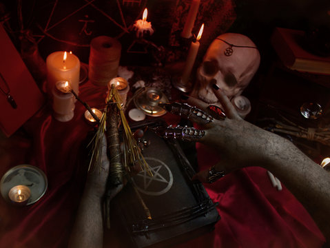 Witchcraft composition with witch's hands carrying out a ritual with Voodoo doll, candles, magic books, magic sphere, crystal, amulets and pentagram symbol. Halloween concept, black magic ritual. 