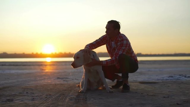 Young man pat his labrador dog at seashore sunset rapid slow motion  