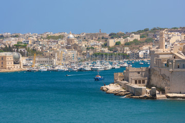 Fototapeta na wymiar malta boats near church with domed roof