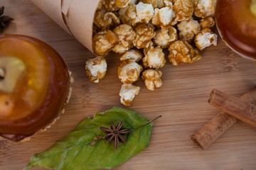 Popcorn, apple and spices on wooden table