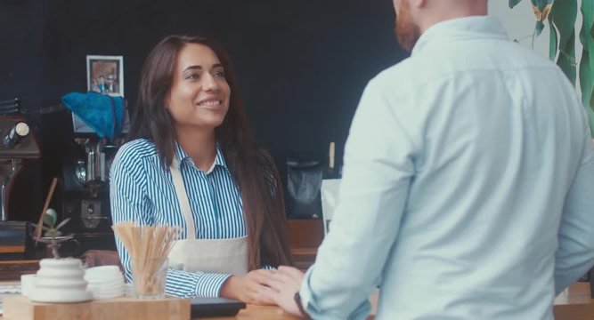 Attractive Caucasian female employee having a conversation with a customer at modern coffee shop. 4K UHD 60 FPS