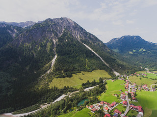 View of bavarian alpine village with a valley and mountains, shot from drone, Bayern, Bavaria, Germany, sunny summer day