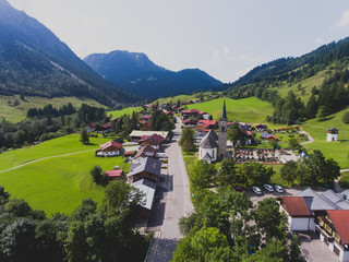 View of bavarian alpine village with a valley and mountains, shot from drone, Bayern, Bavaria, Germany, sunny summer day