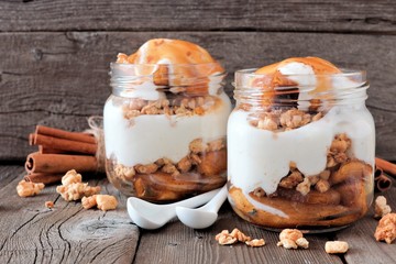 Caramel baked apple parfaits in mason jars on a rustic wood background