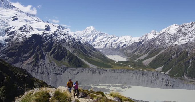 New Zealand Mount Cook nature landscape with hikers tramping hiking in mountain. Couple walking on hike trail route in in Aoraki / Mt Cook National Park. RED EPIC SLOW MOTION.