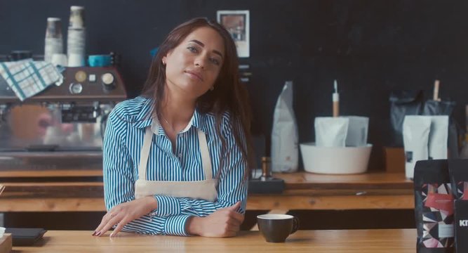 DOLLY IN Portrait of young adult female entrepreneur standing in her modern coffee roastrery, looking and smiling into camera. 4K UHD 60 FPS