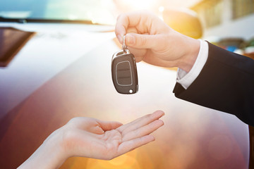 Salesman Handing Key To Woman By New Car