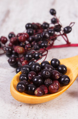Elderberry with wooden spoon on old board, healthy food concept