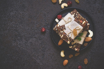 Healthy snack bars of dried fruits and nuts on black concrete background