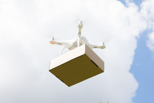 Drone Delivering Parcel Against Sky On Sunny Day