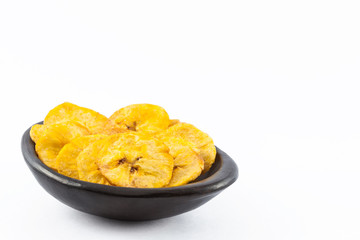 Plantain fried coins in a traditional black clay bowl isolated on white background