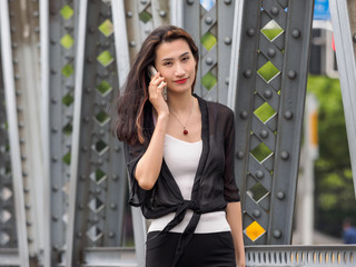 Happy adult Asian woman on the phone, with shanghai garden bridge background.