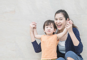 Closeup asian mother and son in happy motion on marble stone wall textured background