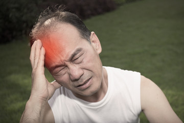 stress  Man holding his head. Senior male on nature background. Grief and pain