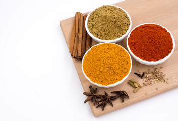 Herbs and spices such as star anise, cinnamon, turmeric, chilli powders and other on a chopping board