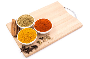 Herbs and spices such as star anise, cinnamon, turmeric, chilli powders and other on a chopping board