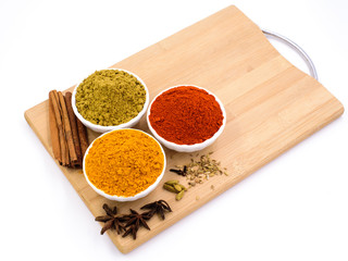 Herbs and spices such as star anise, cinnamon, turmeric, chilli powders and other on a chopping board