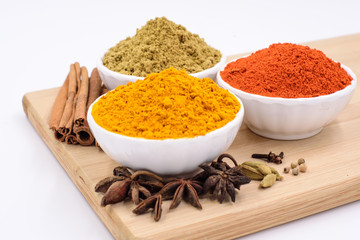 Herbs and spices such as star anise, cinnamon, turmeric, chilli powders and other on a chopping board