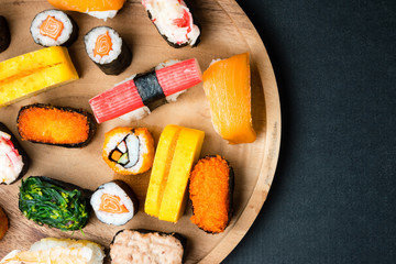 Top view of Sushi set on wooden plate on black background, Japanese food. Free space for text