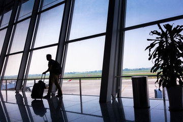 Passengers tourist standing with luggage and watching landing aircraft at terminal airport.,...