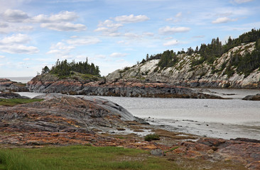 Fototapeta na wymiar Wild rocky coast of Saint Lawrence river, East Canada. Grinding marks of the glaciers are still visible.
