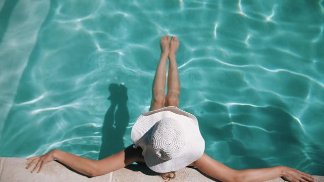 Woman with wide brimmed hat at the pool