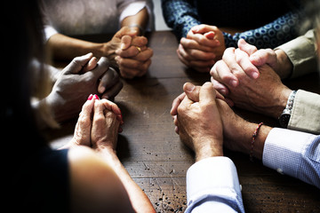 Group of interlocked fingers praying together - obrazy, fototapety, plakaty