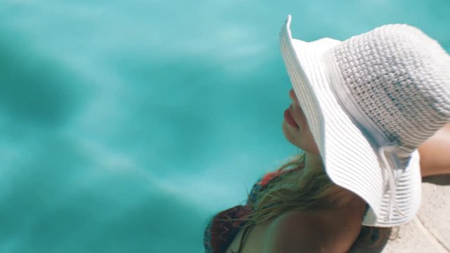 Woman with wide brimmed hat at the pool
