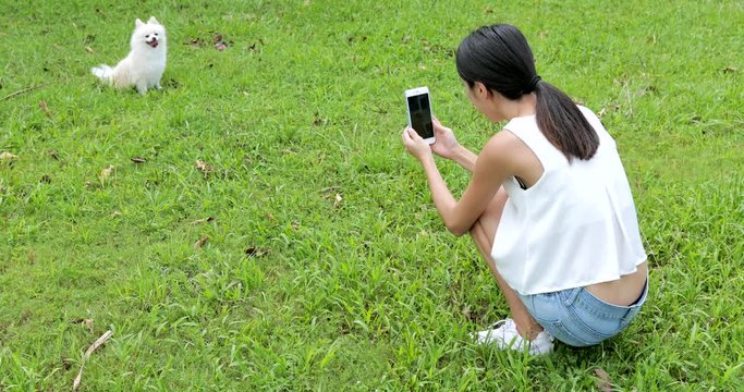 Young Woman taking photo with cellphone on her dog