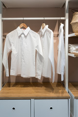 Fototapeta na wymiar White basic shirts hanging in walk in closet with drawer