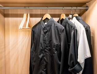 Black basic shirts hanging in the closet.