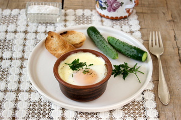 Baked egg with bread and cucumber. Rustic style, selective focus.