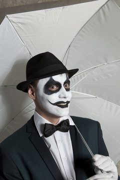 Evil clown holding white umbrella