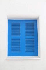 Blue wooden window on white cement wall.