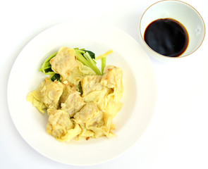 Dumplings on white plate with sweet sauce.