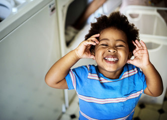 Black kid smiling in the laundry room © Rawpixel.com