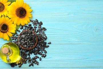 Sunflower oil, seeds and flower on blue wooden background. top view with copy space