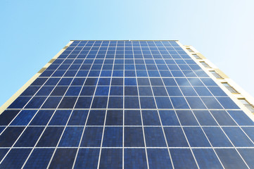 Wall with a wide solar panel against the blue sky. Look up.