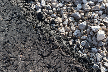 Detail of fresh asphalt on white crashed rocks on a road construction.
