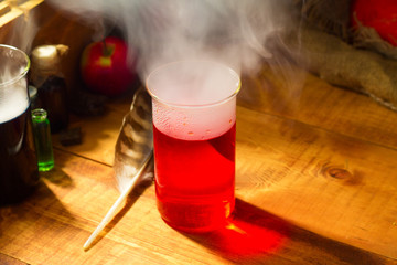 Magical witch lab with fog or smoke and red potion for Halloween wooden background