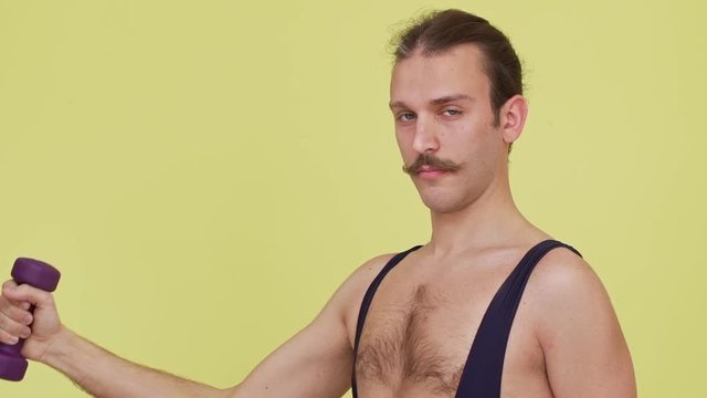 strong concentrated man with athletic look making exercises with dumbbell in slow motion