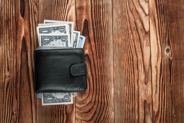 a purse with the American dollars is isolated on a wooden background