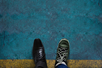 Life Balance Concept for Work and Travel present in top view position by half of Business Oxford and Adventure shoes, Grunge Cement Floor as background