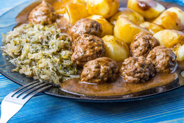 Homemade fried meatballs served with potatoes and cabbage.