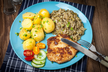 Fried pork chop, baked potatoes and fried young cabbage.